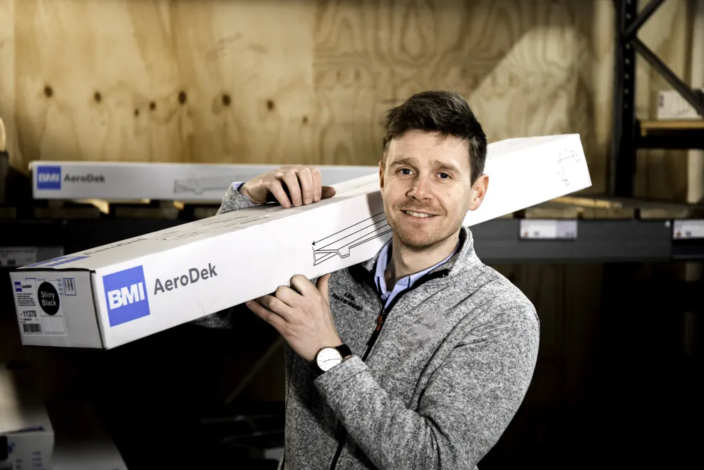 Butikkansatt med en pakke fra BMI med AeroDek produkt, hos en forhandler hvor produktene til BMI blir solgt