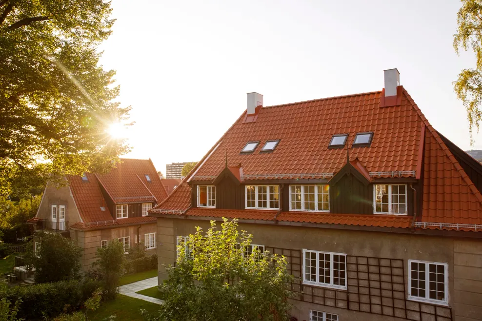 Solnedgang over et hus med Tegltaksteinen nortegl på. Et varmt bilde av et mursteinshus, med klassisk oransj tak i Ullevål Hageby.